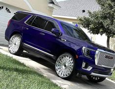 a blue suv parked in front of a house with white rims and chrome wheels