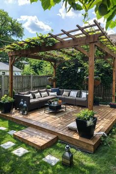 an outdoor living area with couches, tables and potted plants on the grass