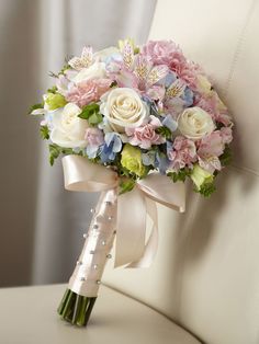 a bridal bouquet sitting on top of a white chair