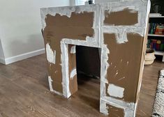 a dog house made out of cardboard with paint all over the walls and floor, sitting on top of a hard wood floor