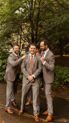 three men in suits and ties are posing for the camera with their arms around each other