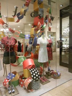 an assortment of hats and scarves on display in a store window with glass walls