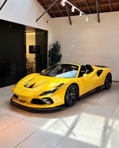 a yellow sports car is parked in a large room with white tile floors and ceilings