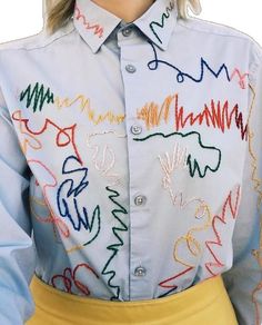 a woman wearing a white shirt with multicolored letters on it