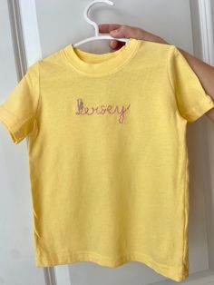 Add this super cute hand embroidered tee to your child's closet!! Rabbit Skin brand tee is used with so many more color options and combinations. Don't see a color you are looking for let us know and I'll be happy to find it for you. Thread colors are limitless and any color combo is welcome. Let us create the color perfect short for you or for a gift!  These also make for great gifts for a baby shower or birthday party! Casual Yellow Embroidered T-shirt, Yellow Cotton Top With Embroidered Graphics, Yellow Cotton Top With Embroidered Logo, Yellow Cotton T-shirt With Embroidered Graphics, Spring Tops With Custom Embroidery, Basic Embroidered Cotton Tops, Cotton Tops With Multicolor Embroidery And Logo, Yellow Embroidered Short Sleeve T-shirt, Yellow Embroidered Cotton Shirt