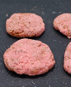 four hamburger patties on a baking sheet ready to be cooked