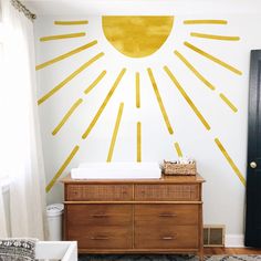 a baby's room with sun painted on the wall and crib in the foreground