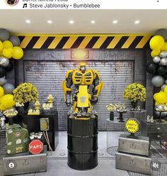 a room filled with lots of decorations and balloons in the shape of a robot standing on top of a barrel