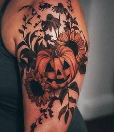 a woman's arm with sunflowers and a pumpkin tattoo on her shoulder