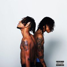 two men with dreadlocks and tattoos on their arms are standing in front of an orange background