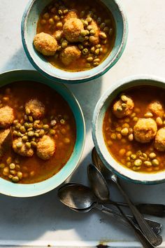 three bowls of soup with meatballs and beans on the top one has spoons