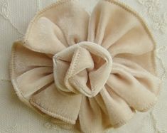 a close up of a cloth flower on a white surface with lace and crochet