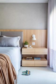 a bed sitting next to a night stand on top of a white carpeted floor