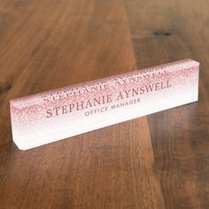 a wooden table with a white and pink business card holder on it's side