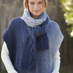 a woman wearing a blue knitted ponchy with a scarf around her neck