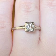 a close up of a person's hand with a diamond ring on their finger