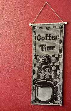 a cross stitch banner hanging on a red wall with the words coffee time written across it