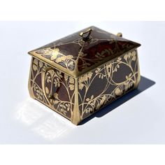 an ornate gold and black box with flowers on it's lid sits on a white surface