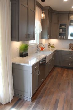 a kitchen with wooden floors and gray cabinets