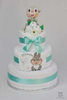 a three tiered diaper cake with an animal on top and blue ribbon around the edge