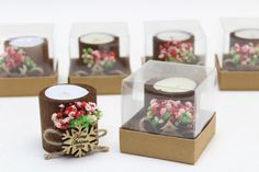 four candles are in small boxes with flowers on them, and one candle is wrapped in brown paper