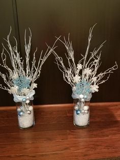 two vases with branches and balls in them