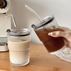 a person is holding a glass with some liquid in it next to a toaster