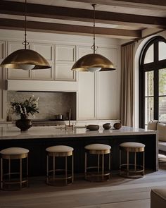 a kitchen island with stools and lights hanging from it's ceiling over the counter