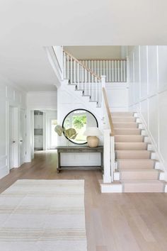 a white staircase leading up to a living room with a round mirror on the wall