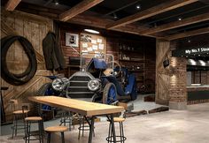 an old timey car is parked in a garage with wooden tables and stools