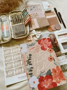 the contents of an organized planner spread out on a bed with flowers and other items