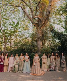 a group of women standing in front of a tree