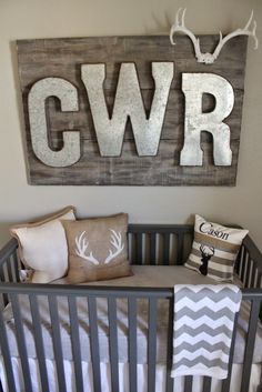 a baby's room with a crib and deer head hanging on the wall