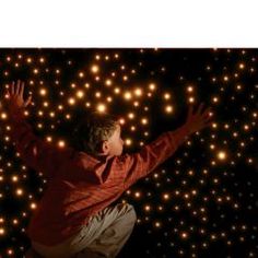 a boy is jumping in the air with his arms spread out and glowing balls all around him