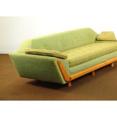 a green couch sitting on top of a brown carpet