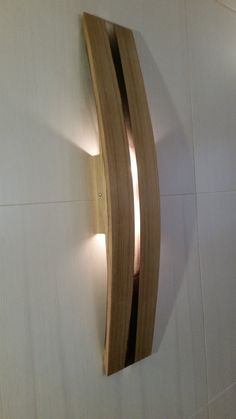 a wooden wall light mounted to the side of a white wall with two lights on it