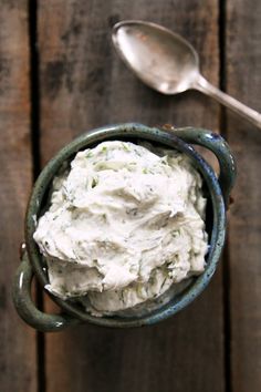 a bowl filled with whipped cream sitting on top of a wooden table next to a spoon