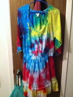 a tie - dyed dress hangs on a door hanger in front of a wooden door