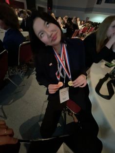 a young woman sitting in a chair with medals around her neck