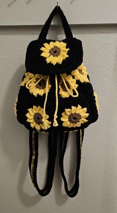 a crocheted sunflower backpack hanging on the wall