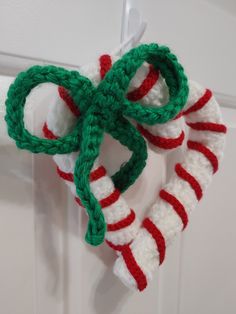 a crocheted christmas ornament hanging on a door handle with candy canes