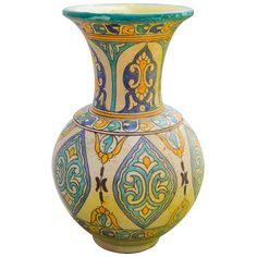 an ornate vase with blue, yellow and green designs on it's sides against a white background