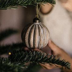 a person is holding a christmas ornament on a tree