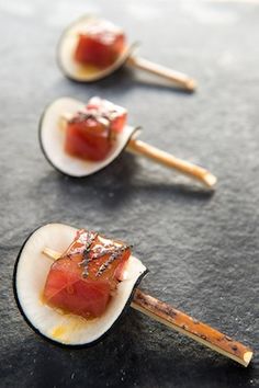 three small pieces of food sitting on top of a table next to chopsticks