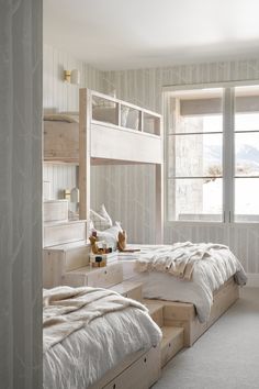 a bedroom with bunk beds and two windows in it's side wall, along with white carpeted flooring