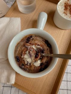 a bowl of oatmeal is sitting on a tray next to two cups