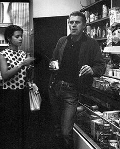 black and white photograph of two people standing in front of a store shelf with items on it