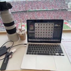 an open laptop computer sitting on top of a desk next to a camera and cup