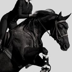 a woman riding on the back of a black horse with her legs spread out in the air