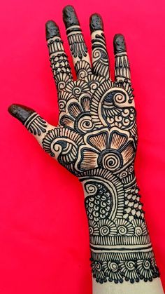 the hand is decorated with henna and paisley designs on it's palm, against a pink background